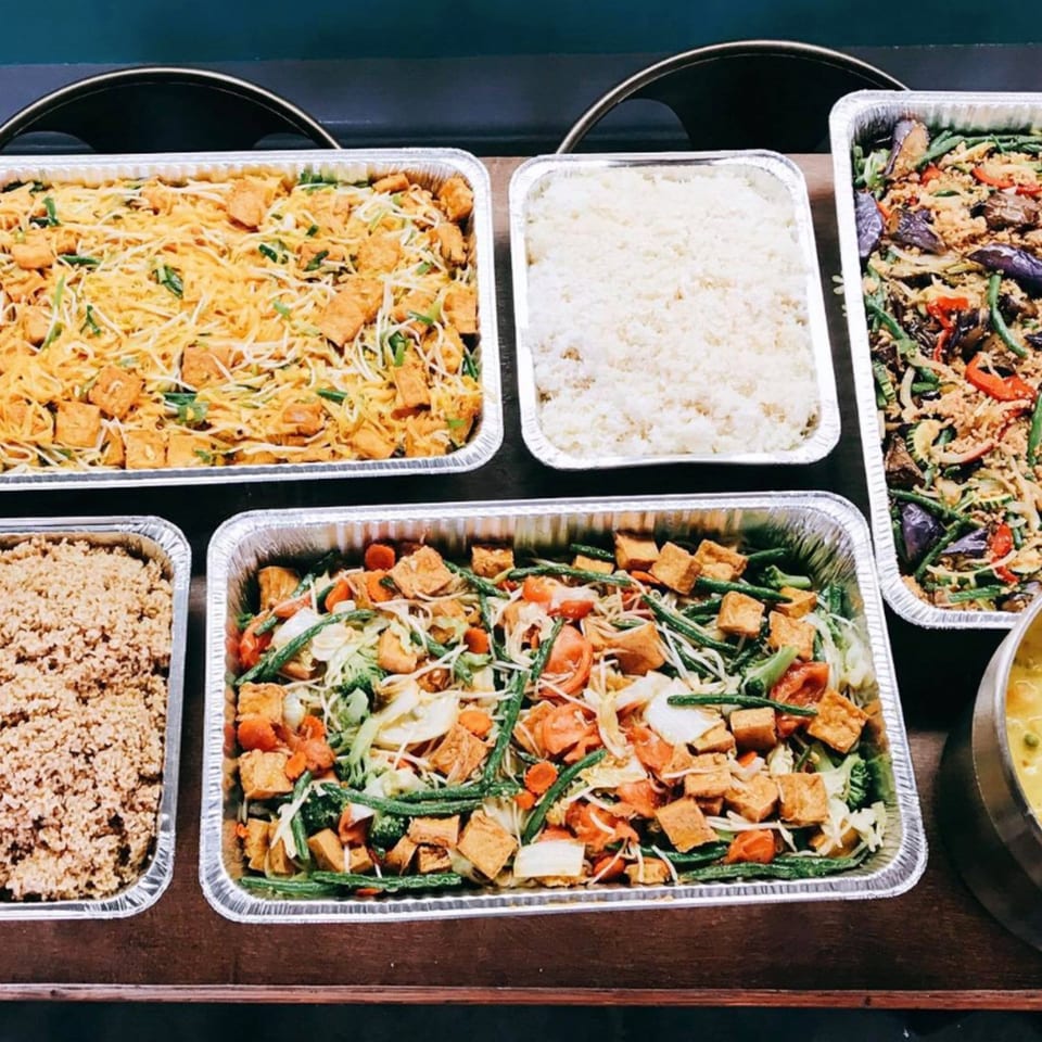 STIX Eatery's Asian catering spread with noodles, rice, and vegetable dishes in foil trays.