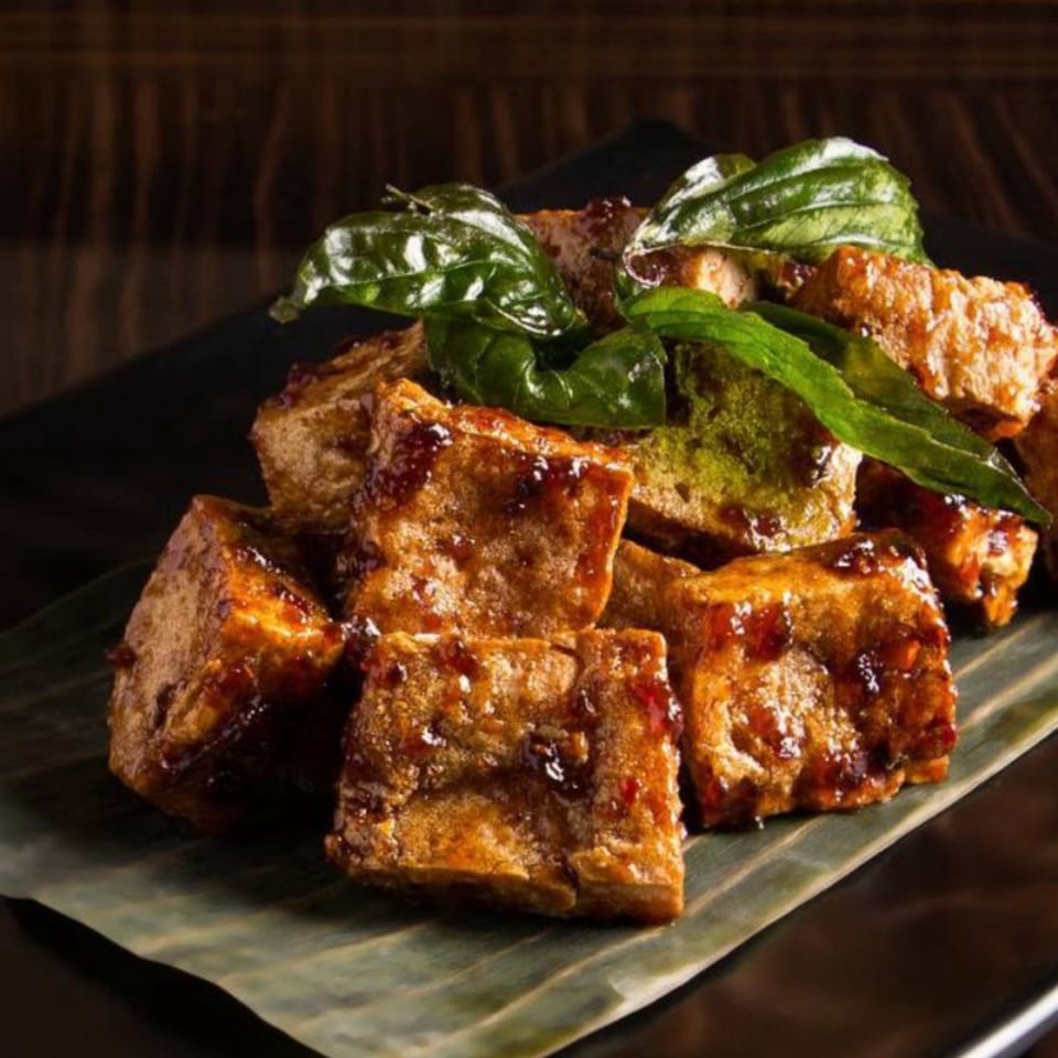 Crispy STIX Eatery tofu cubes glazed with sauce and garnished with fresh green basil leaves.