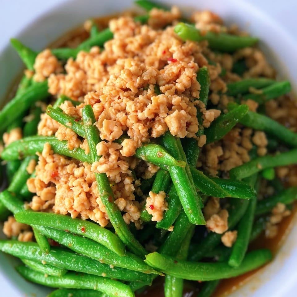 STIX Eatery's green beans stir-fried with minced chicken, glistening with sauce in a white bowl.