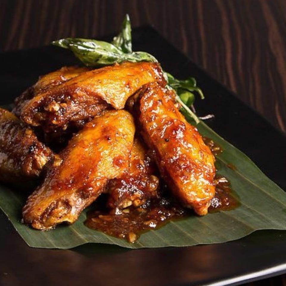 STIX Eatery's Asian-style chicken wings, glazed in a rich sauce, served on a banana leaf.
