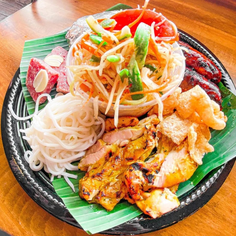 STIX Eatery's Asian platter with papaya salad, grilled chicken, noodles, sausage, and pork rinds.